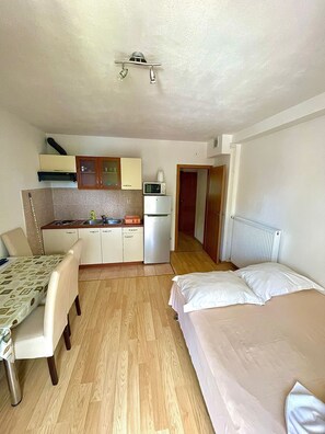 A compact room with a kitchenette, a dining area, and a bed. - Apartments Luka (Omis)