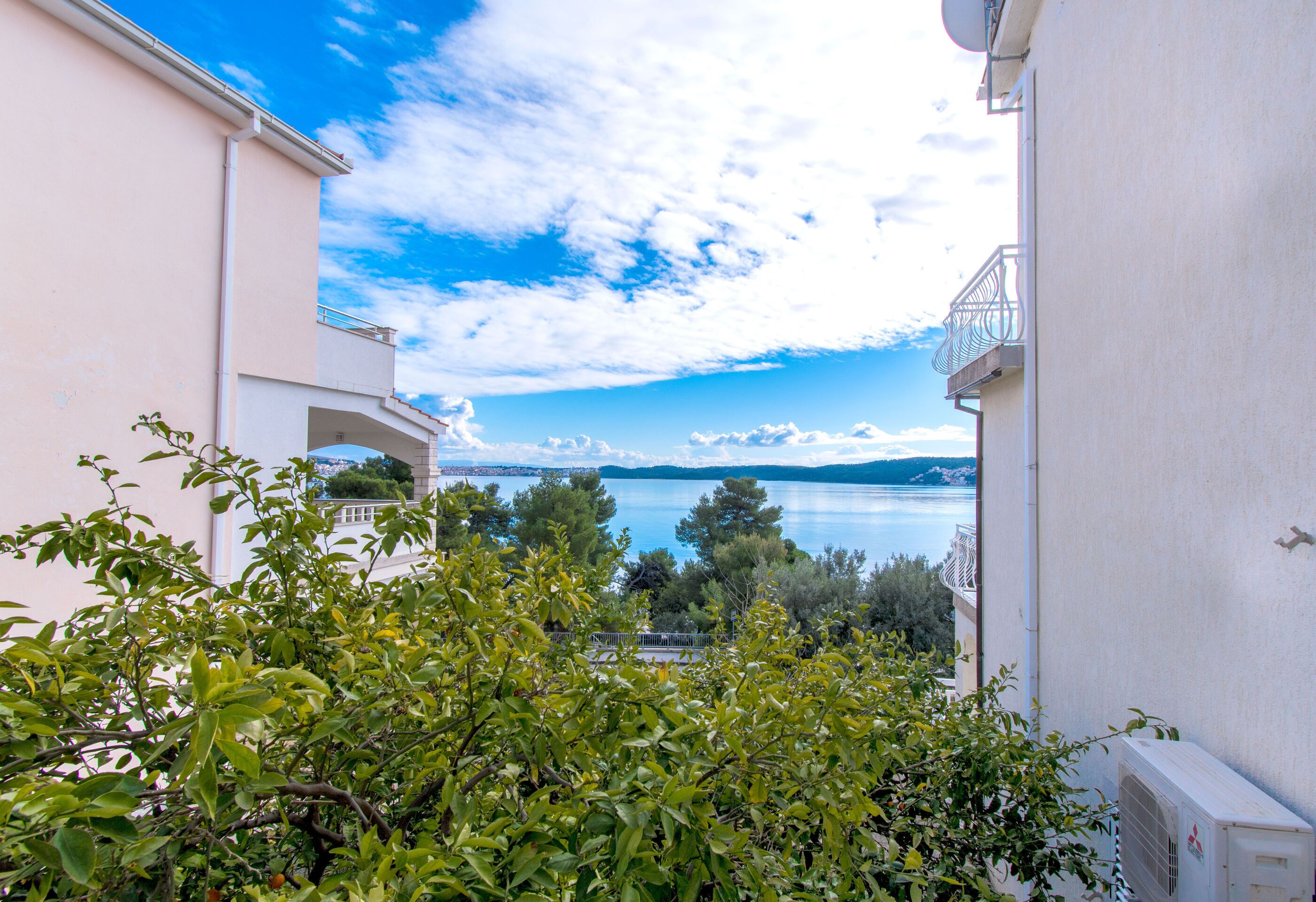 A view of a building with a balcony overlooking a body of water and trees.