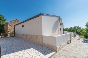 A building with a stone facade, a flat roof, and a paved courtyard.
