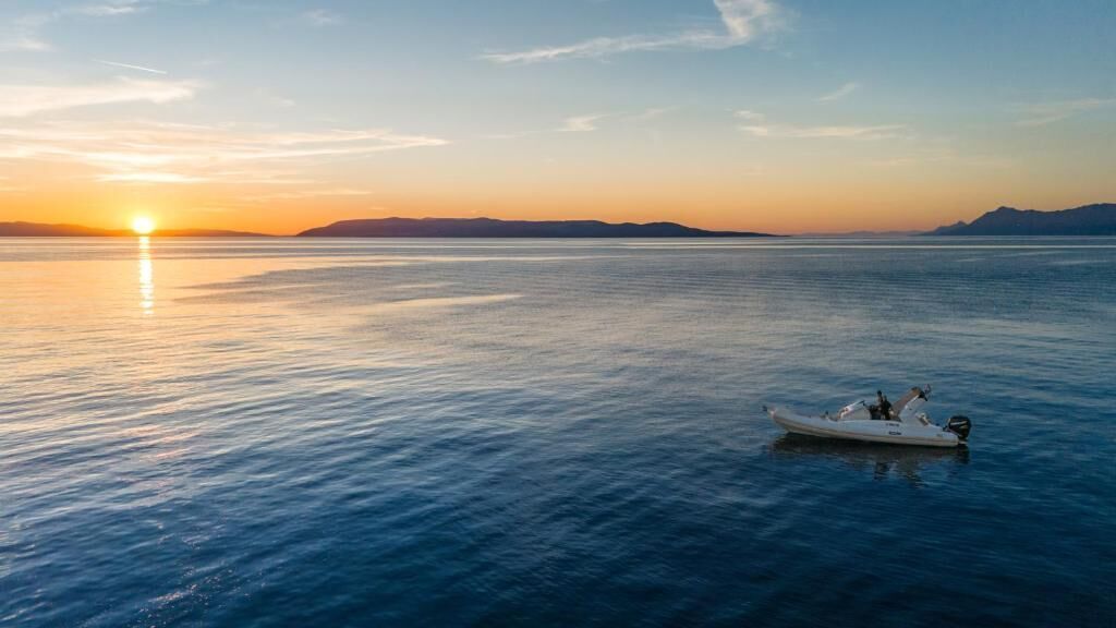 A boat on calm water with a sunset in the background.