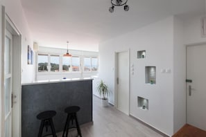 A modern kitchen with a bar area, large windows, and a potted plant. - Apartment Town and Beach (Makarska)