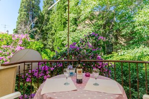A balcony with a table set for two, a bottle of wine, and glasses. - Apartment Green Rustic (Split)
