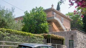 A stone building with a balcony, a car parked in front, and lush greenery. - Apartment Green Rustic (Split)