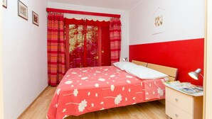 A bedroom with a bed, a nightstand, a desk, and a window with curtains. - Apartment Green Rustic (Split)