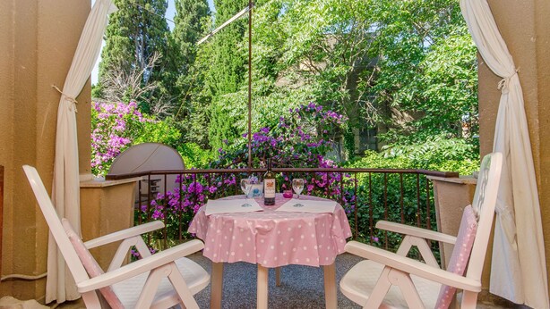 A balcony with a table and chairs, a view of trees and flowers, and a pergola structure. - Apartment Green Rustic (Split)