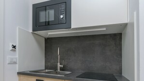 Una cocina moderna con microondas integrado, grifo de acero inoxidable y armarios de madera.