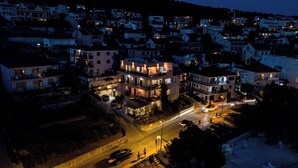 A multi-story residential building with balconies, a driveway, and a street with vehicles. - Apartment Sunset 3 (Trogir)