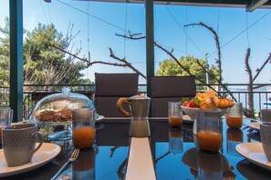 Ein Frühstückstisch mit Kaffeekanne, Obstschale und Glas Orangensaft.