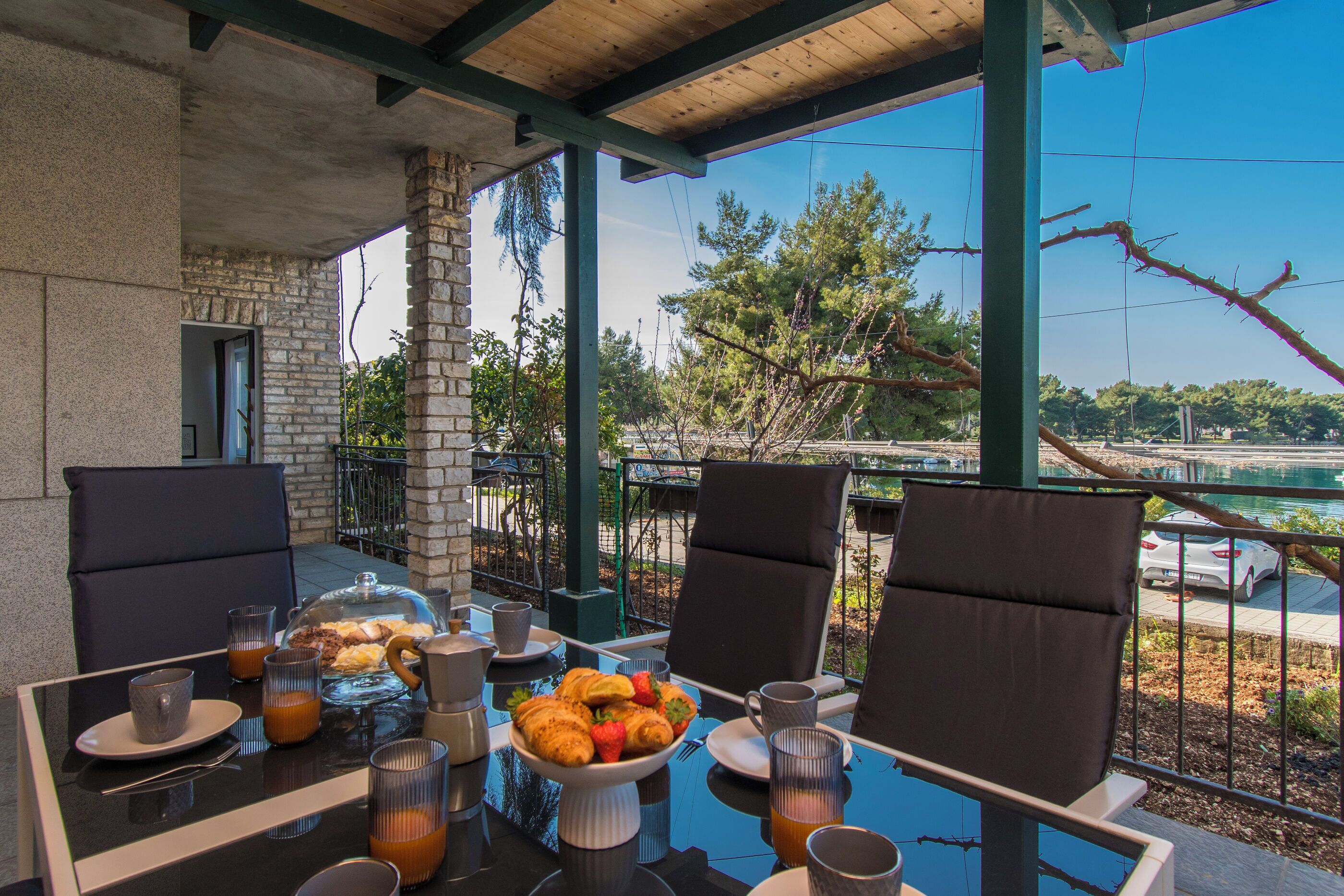 A breakfast setup with a table, chairs, and a view of a bridge and trees.