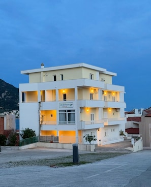 A multi-story building with balconies, a sign reading 'APARTMANTI LULIĆ,' and a view of the surrounding area. - Apartments Cvita (Igrane)