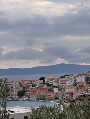A coastal town with buildings along the waterfront, a marina, and mountains in the background. - Apartments Cvita (Igrane)