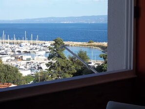 Ein Yachthafen mit Booten, freiem Blick auf das Meer und Hügeln im Hintergrund.