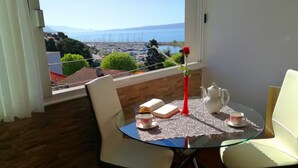 Una zona de menjador amb una taula preparada per a dues persones, un ram de flors en un vas, un llibre i una teiera sobre una tovallola de taula d'encaix.
