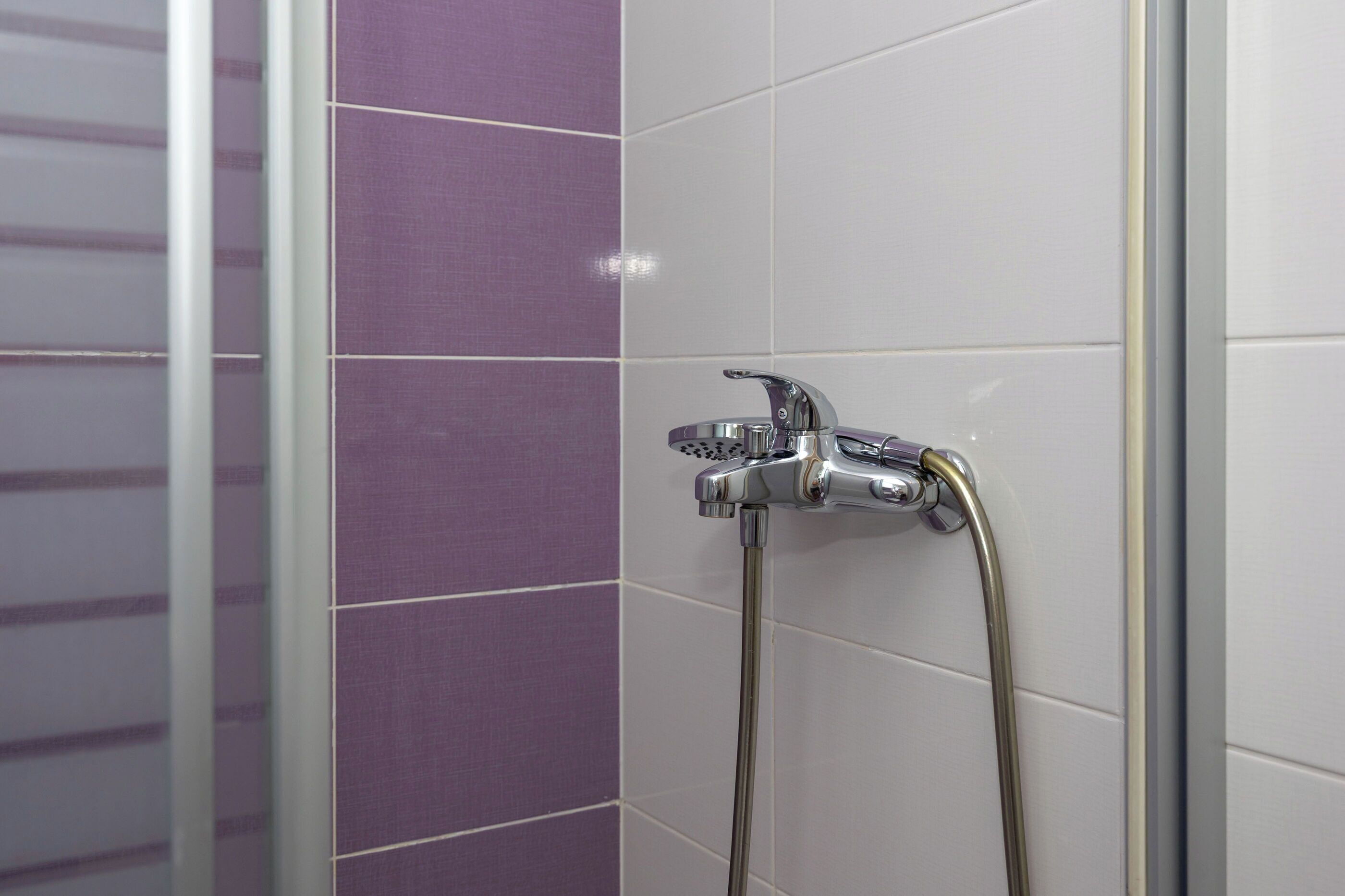 Douchegedeelte met een chromen kraan en een handdouche.