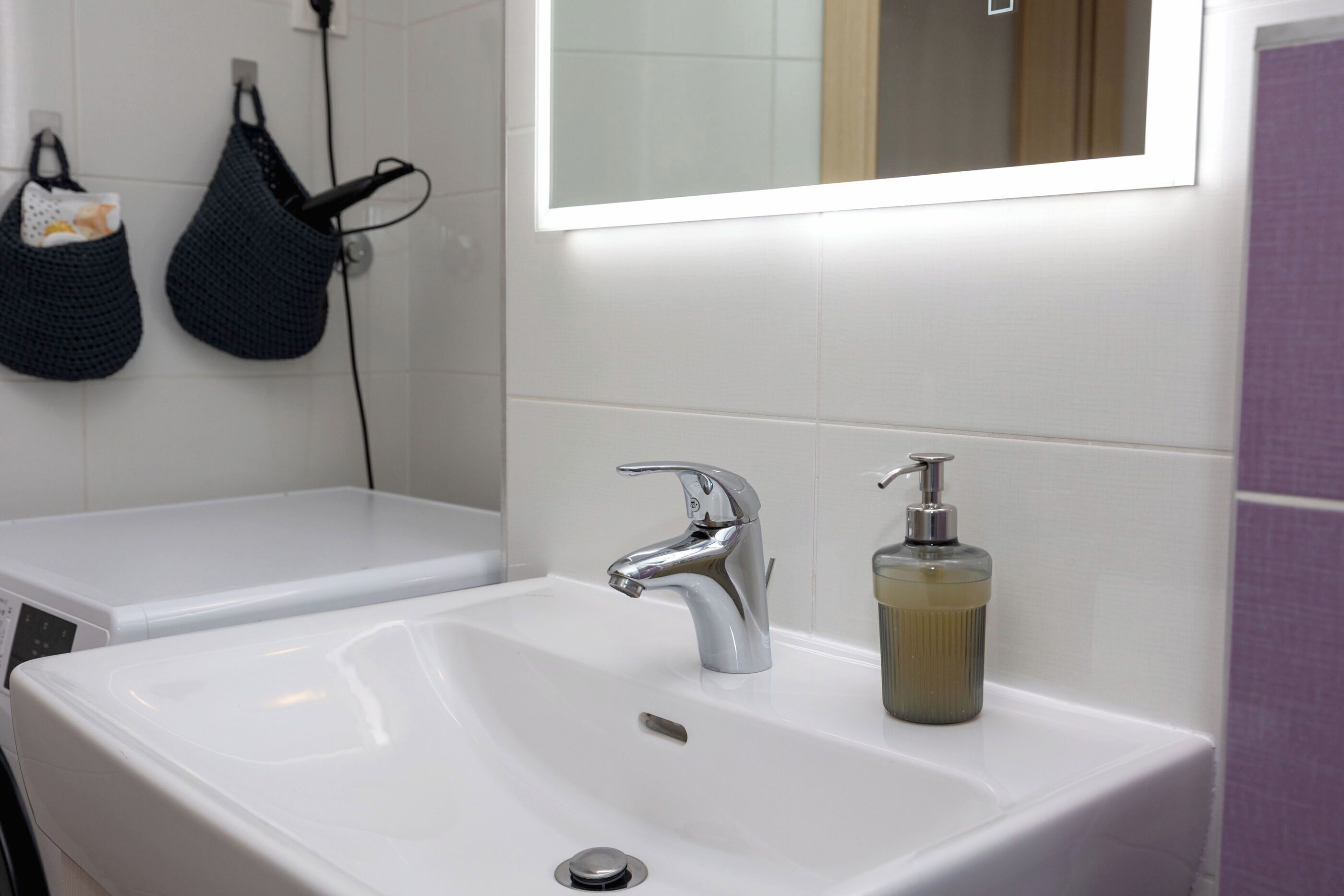 A bathroom with two sinks, a mirror, and a soap dispenser.