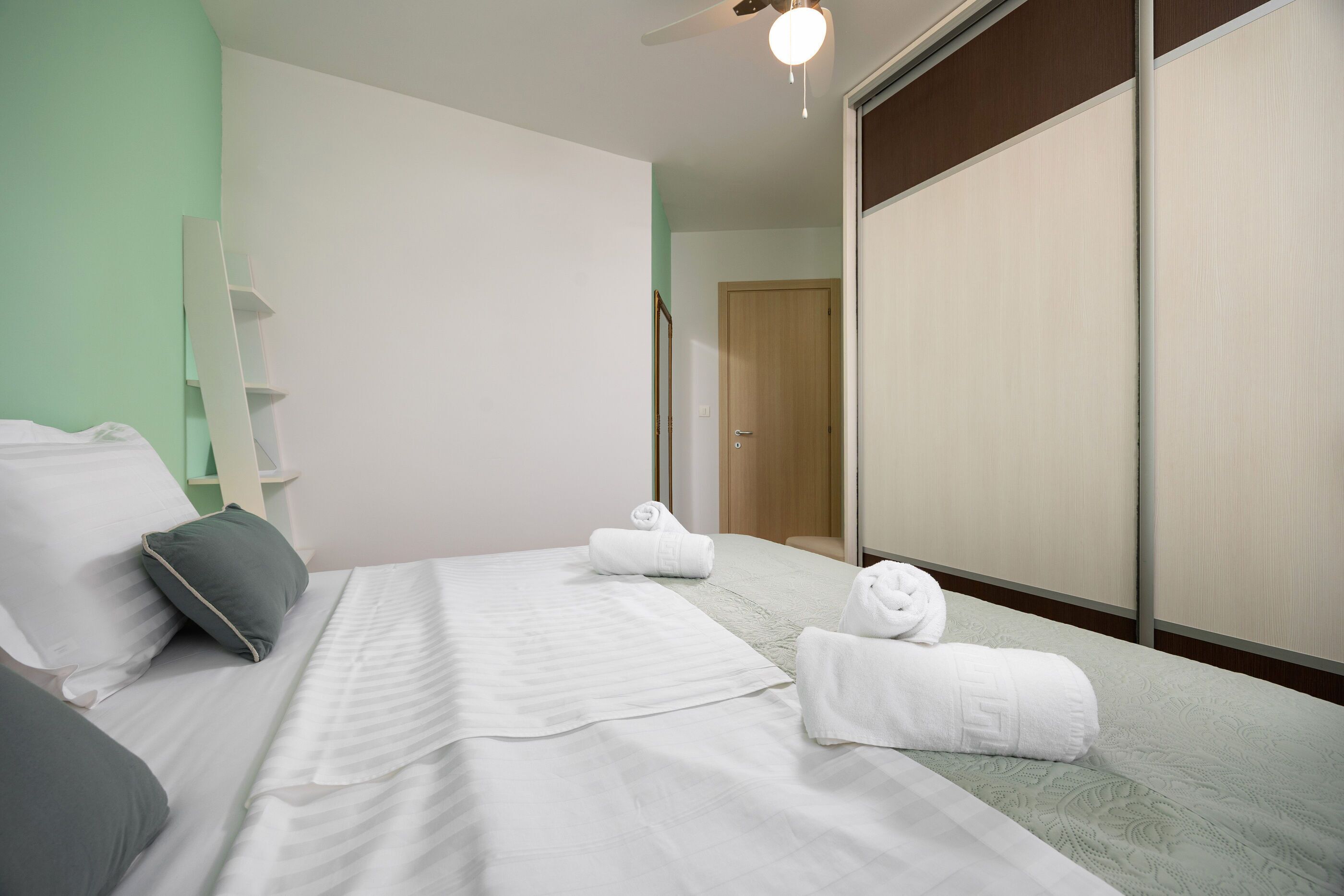 A hotel room with a bed, a wardrobe, and a mirror.