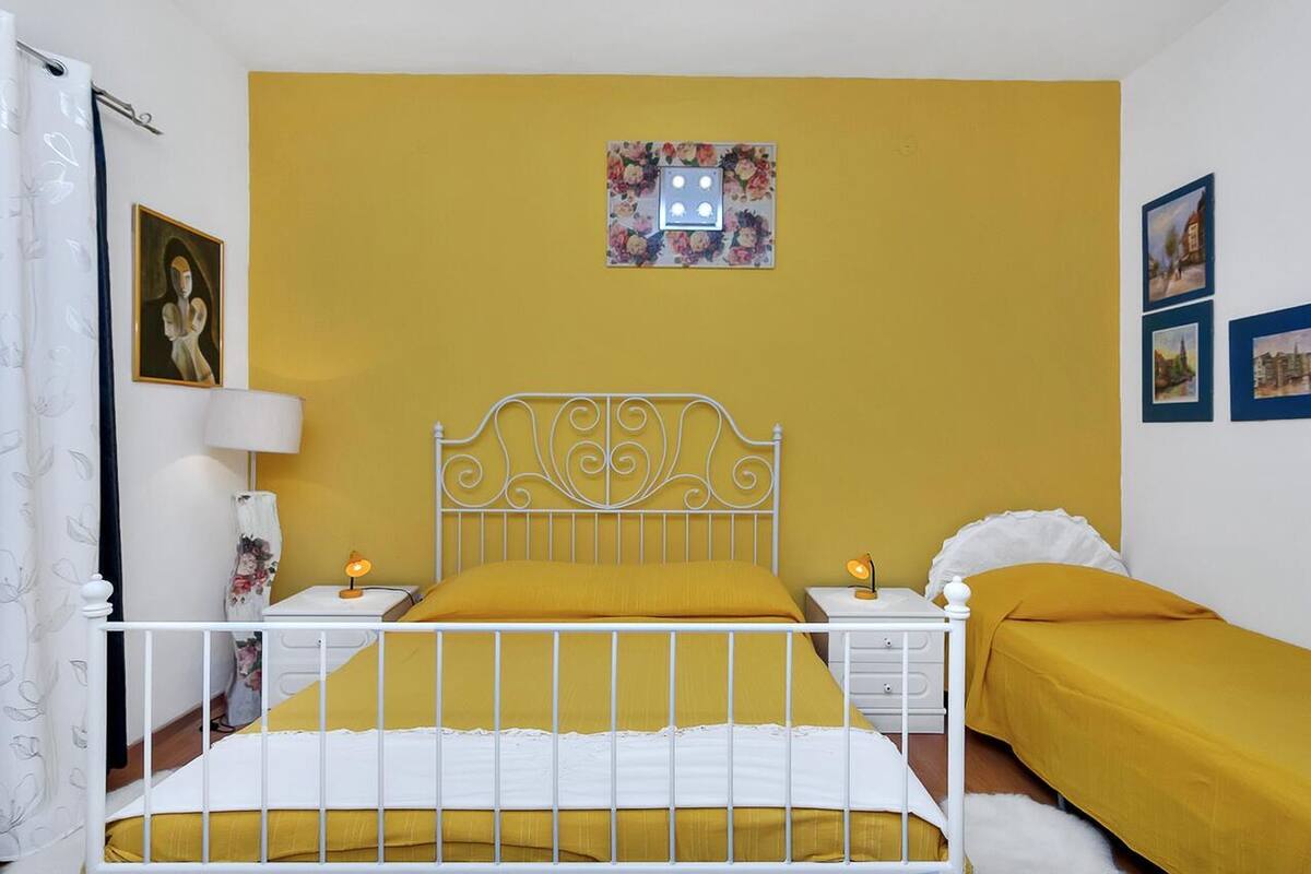 Una habitación con cama, mesitas de noche, una lámpara e interruptor de luz en la pared.