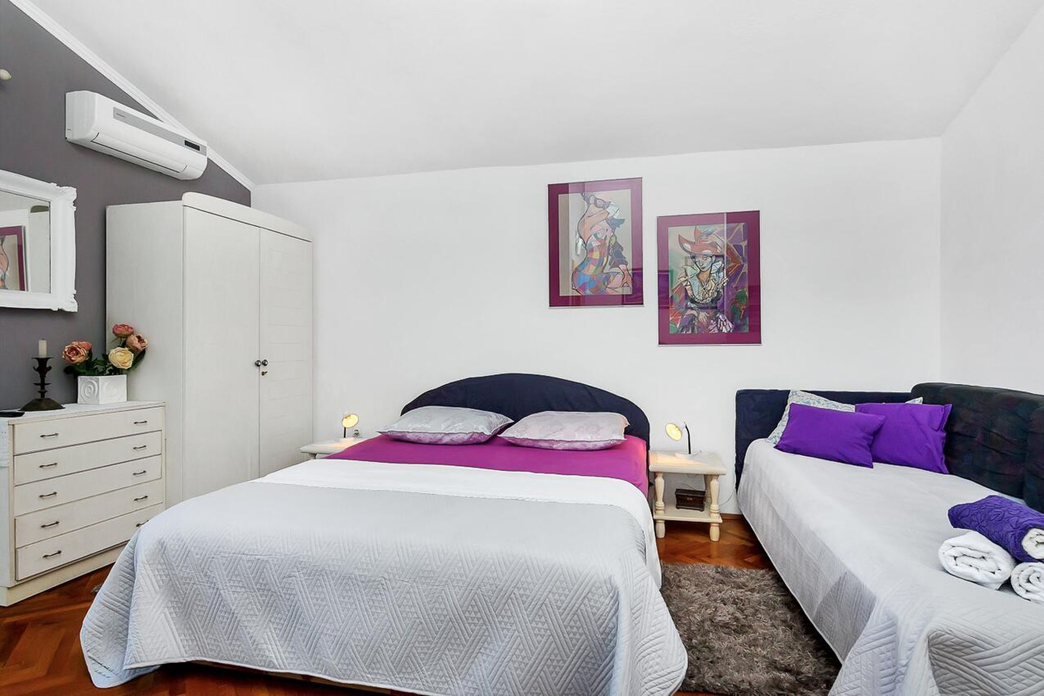 Ein Schlafzimmer mit zwei Betten, einem Kleiderschrank und Bildern an der Wand.