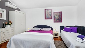 Una camera da letto con due letti, un armadio e opere d'arte alle pareti.