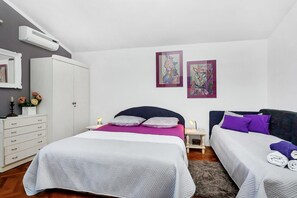 A bedroom with two beds, a wardrobe, and artwork on the wall. - Apartments Maja (Makarska)