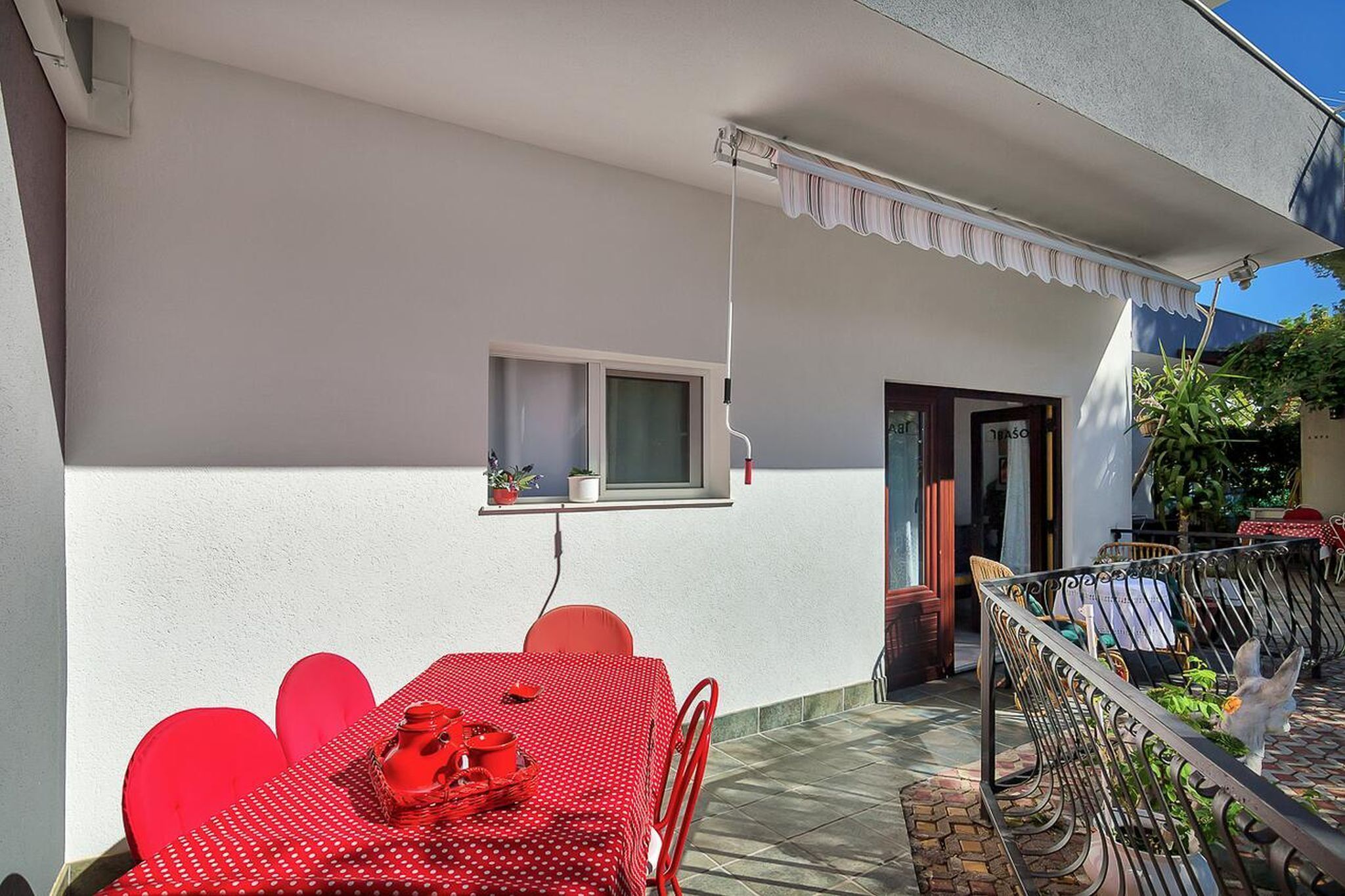 Un conjunto de mesa y sillas rojas en un patio con una pared blanca y una ventana.