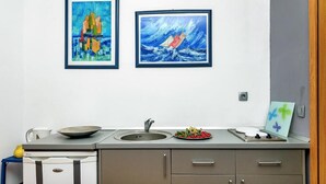 Una cucina con lavello, fornello e un piano di lavoro. Due quadri appesi alla parete.