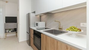 A modern kitchen with a microwave, oven, sink, and a bowl of fruit on the counter. - Apartment Beachfront Daria (Split)