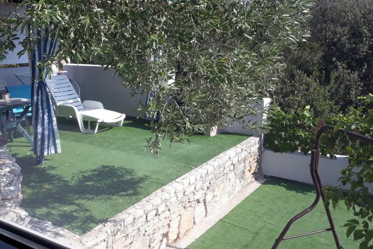 A patio with a table and chairs, a small tree, and a stone wall.