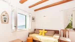 Una habitación acogedora con cama, una mesita, una silla y ventana con vista al mar.