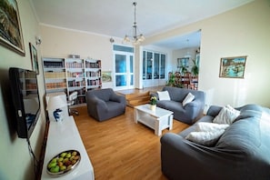 A living room with a sofa, armchair, coffee table, and bookshelves. - Villa Flower Garden With Pool (Donji Prolozac)
