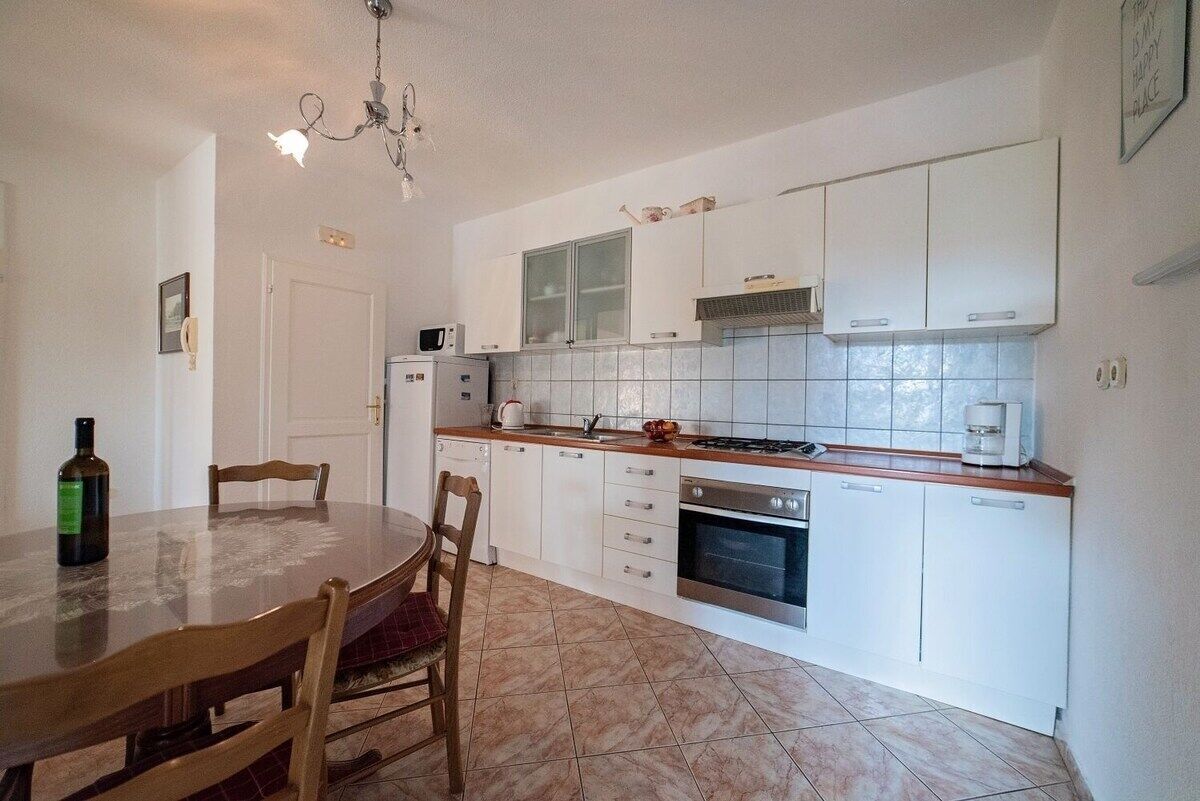 A kitchen with white cabinets, a microwave, a stove, and a dining table with chairs.