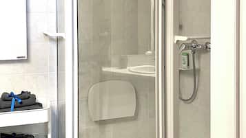 A shower with a glass door, a white sink, and a towel rack with towels.