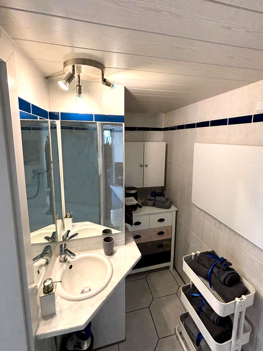 Un baño pequeño con lavamanos, espejo y perchero.
