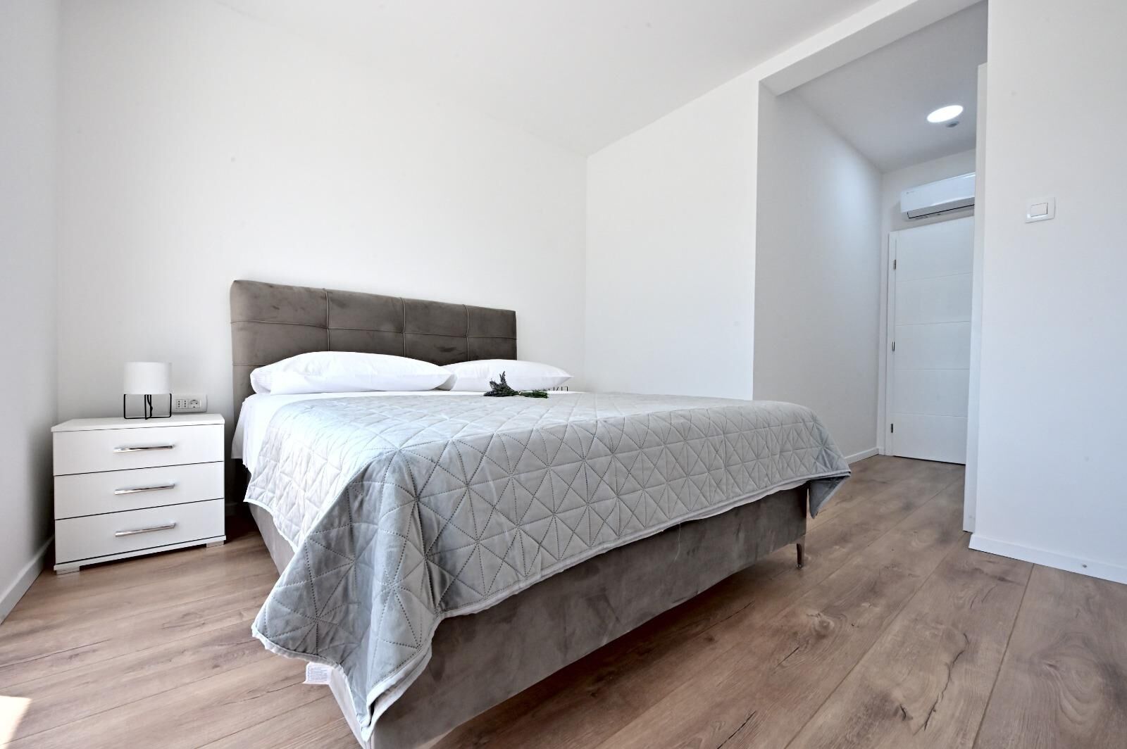 A bedroom with a bed, a nightstand, and a door.