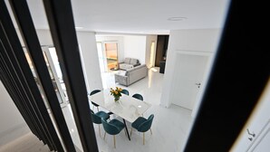 Et moderne interiør med spiseplads, sofa og køkken.