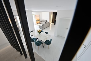 A modern interior with a dining area, a sofa, and a kitchen. - Villa Serenity With Heated Pool (Donji Prolozac)