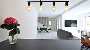 Et moderne interiør med et spisebord, en sofa og en vase med blomster.