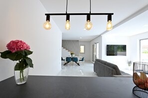 A modern interior with a dining area, a sofa, and a vase with flowers. - Villa Serenity With Heated Pool (Donji Prolozac)