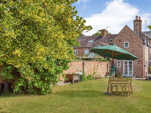 A backyard with a wooden table, chairs, and a green umbrella. - Wards Court 1, Frampton On Severn (Gloucester)