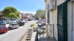 A street view with parked cars, a building with a green shutter, and a sign for 'SERVIS MOBITELA.' - Apartment Oscar (Split)