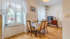 A dining area with a table, chairs, a television, and a cabinet. - Apartment Oscar (Split)
