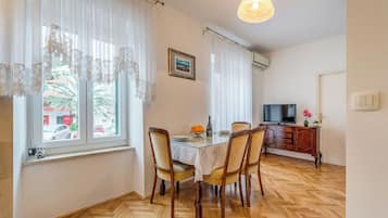 A dining area with a table, chairs, a television, and a cabinet.