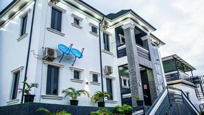 A modern building with a white facade, multiple windows, and a balcony. - Nouveau Apartment (Abuja)