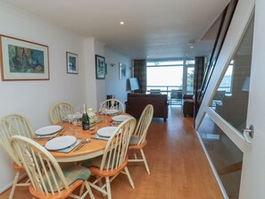 A dining area with a round table, chairs, and a sofa in the background.