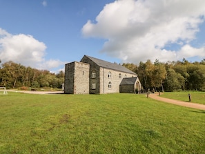 Ein Steinhaus mit einer großen Rasenfläche davor.