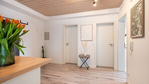 Ein modernes Interieur mit Holzboden, einer Rezeption, einem Blumenstrauß und gerahmten Kunstwerken an den Wänden.
