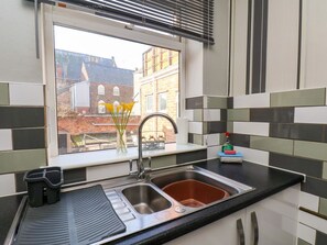 Eine Küche mit Fenster, einer Spüle und Fensterbank mit Blumen in einer Vase.