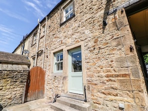 A stone building with a wooden gate, a white door, and a window. - The Smithy, Barnard Castle (Barnard Castle)