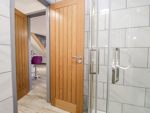 A hallway with a wooden door, a glass shower enclosure, and a purple chair. - The Annex, Ulverston (Ulverston)