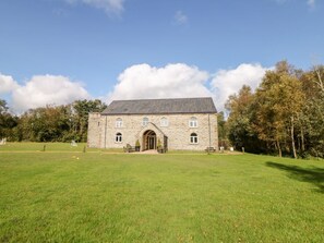 A stone building with a central entrance, surrounded by a grassy field and trees. - Hassop, Matlock - A Charming Retreat (Matlock)